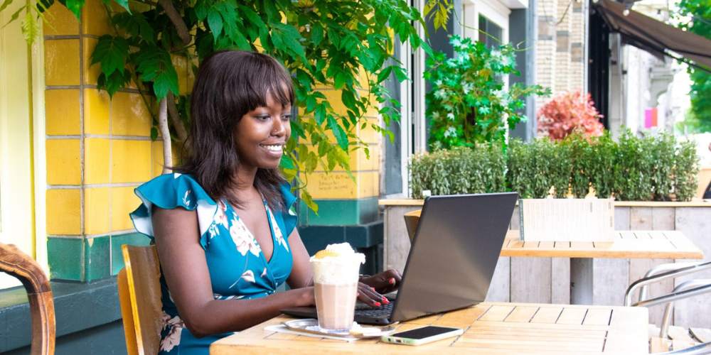 Ina buiten aan het werk met de laptop en een koffie